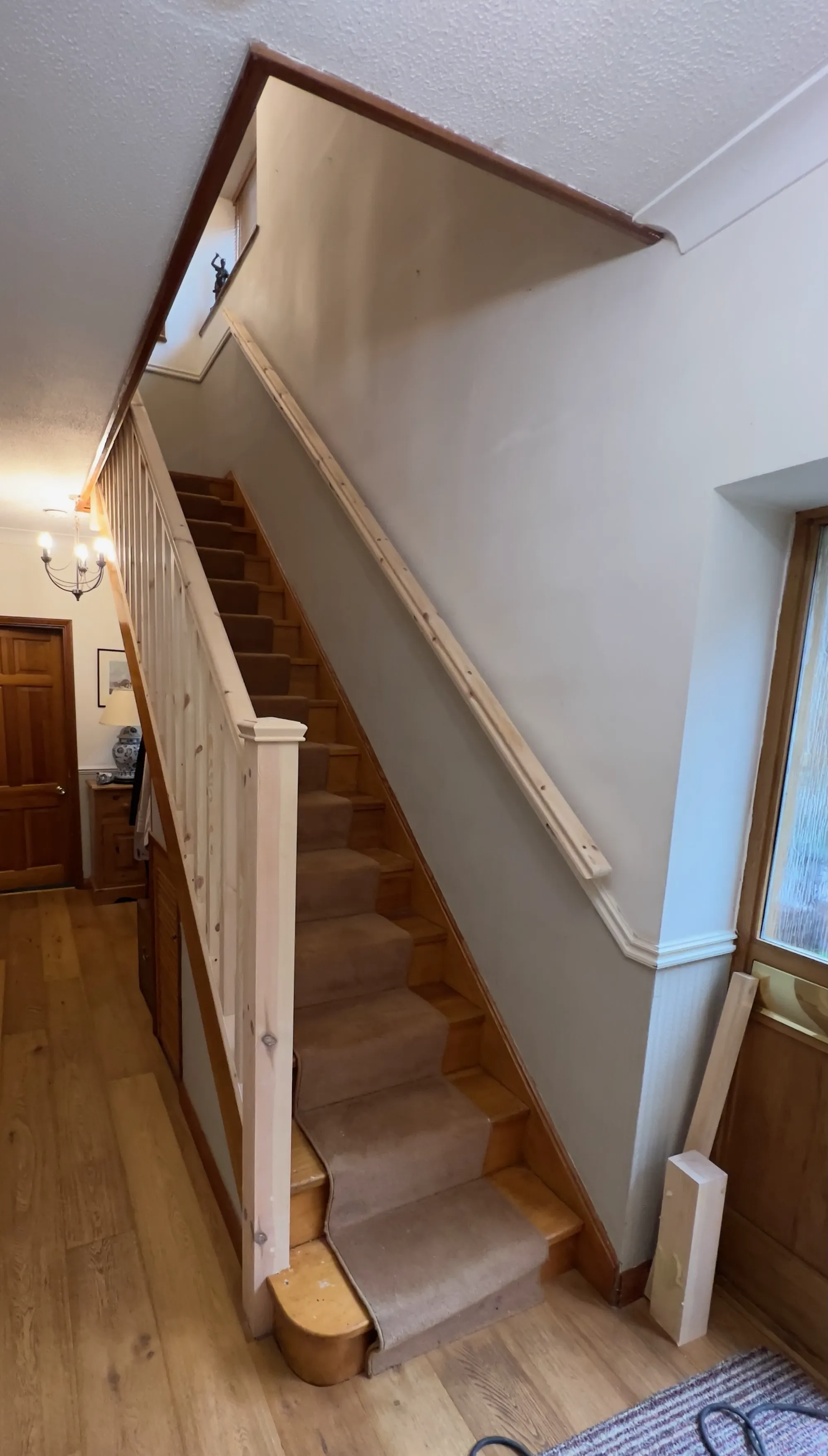 A staircase with a modern wall-mounted handrail and upgraded balustrade featuring square posts for improved safety and support.