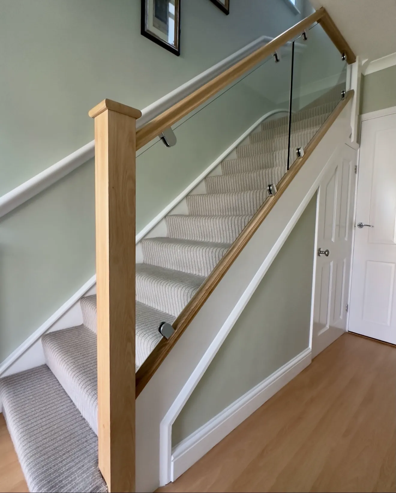 Bespoke staircase with oak handrail, newel post, and glass balustrade. Modern staircase refurbishment by Kent staircase specialists.