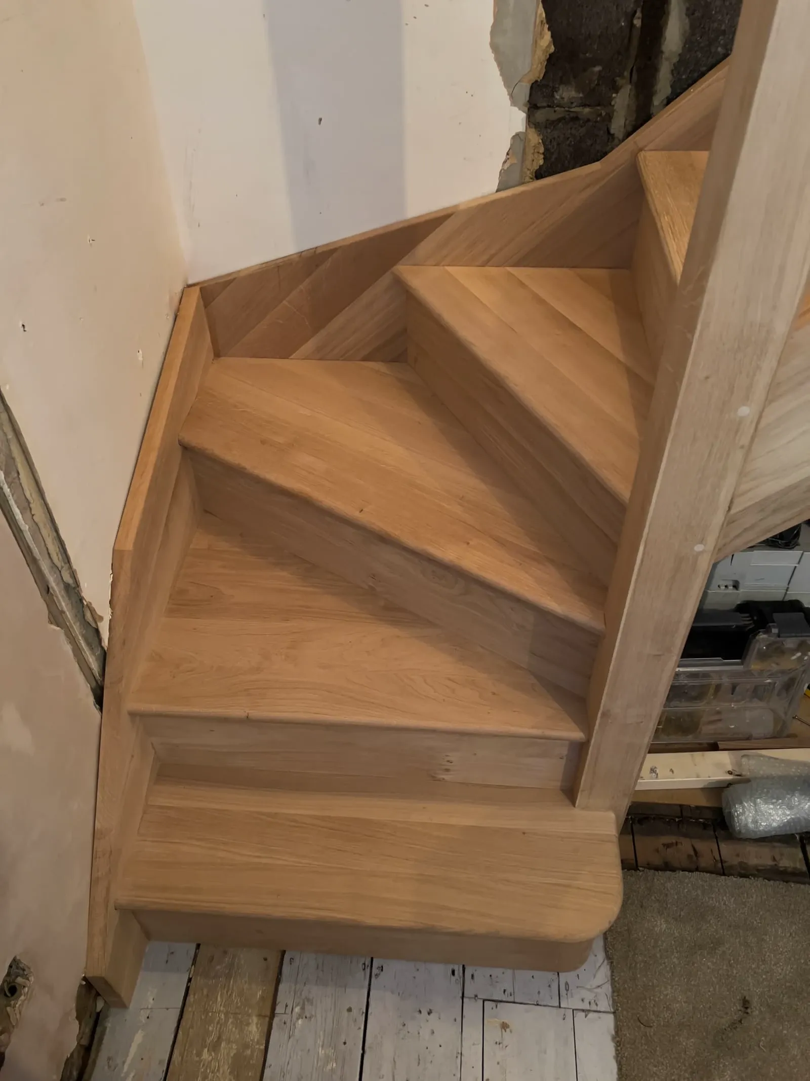 A close-up of newly installed oak winder staircase steps, showcasing detailed joinery and smooth finish.