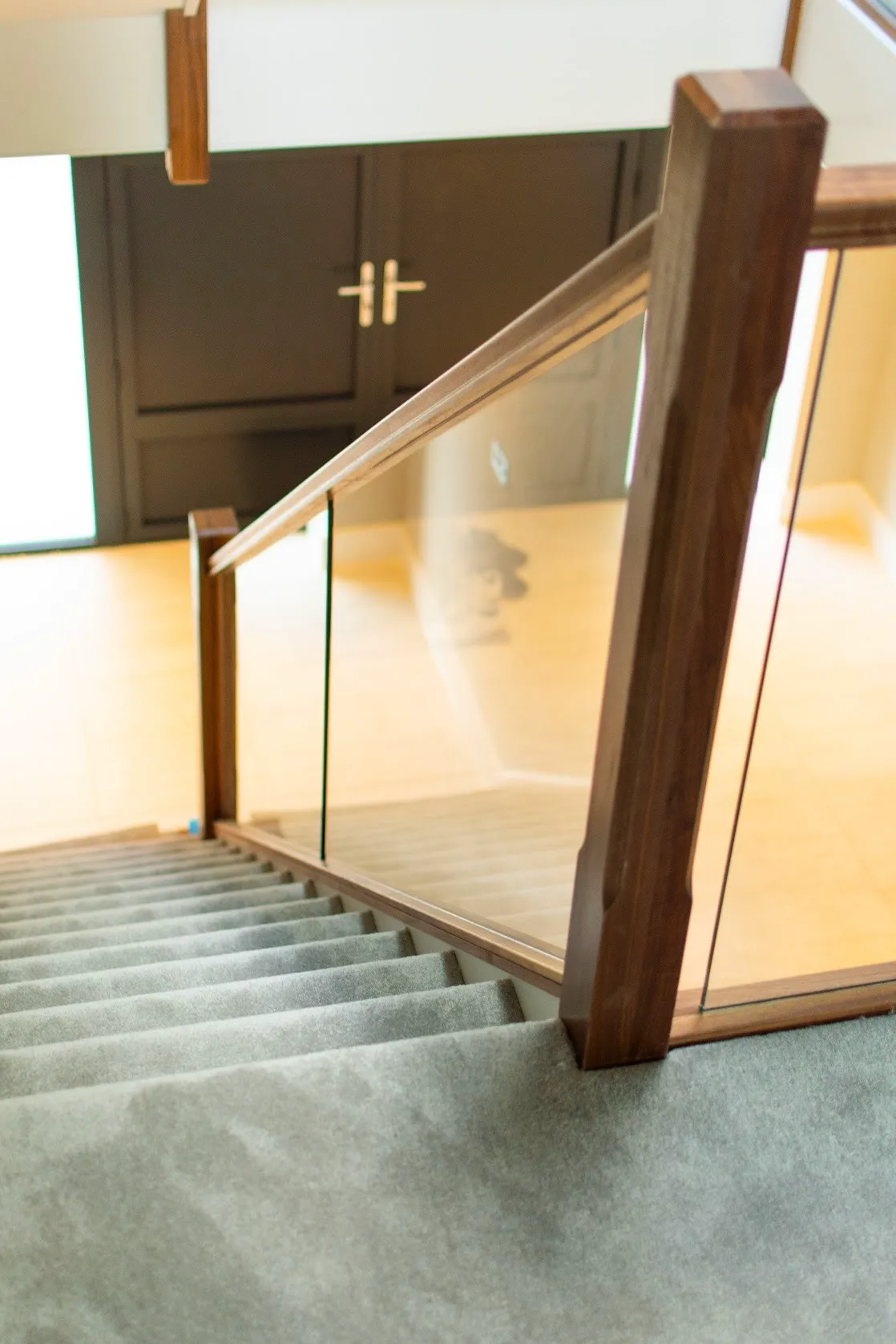 Bespoke staircase with Walnut newel posts, handrail, and glass balustrades. Modern staircase refurbishment by Kent staircase specialists.