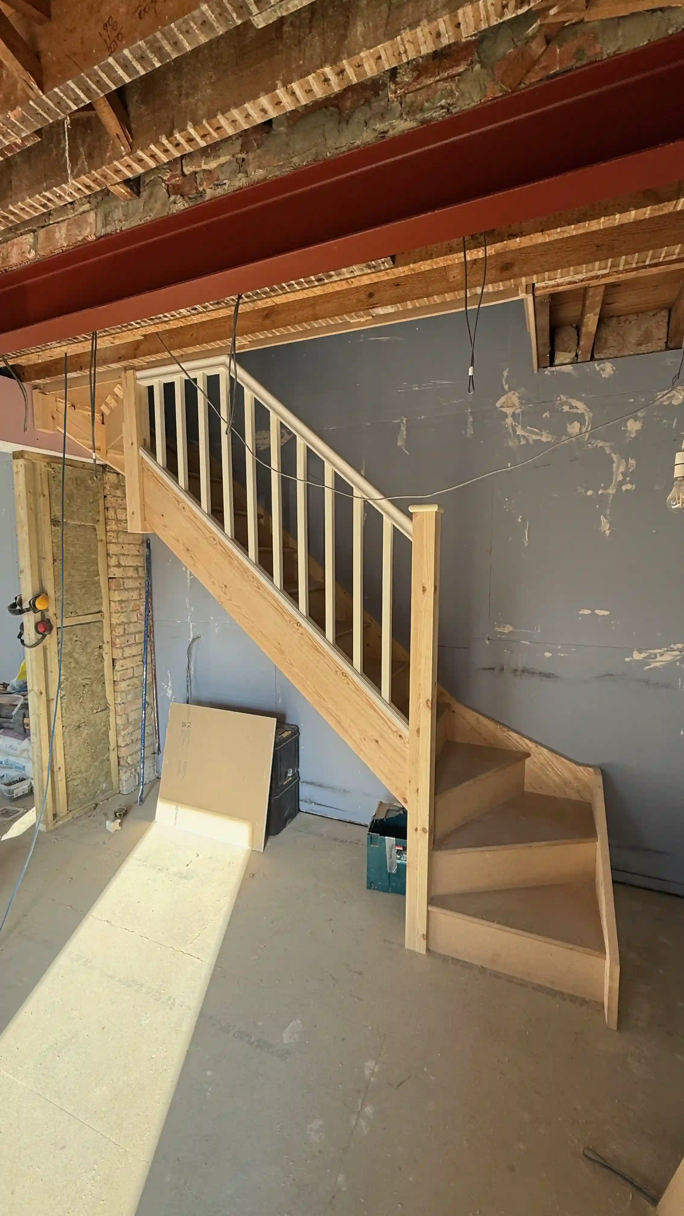 Newly installed wooden staircase with winder steps in an unfinished space. Bespoke staircase installation in Kent.