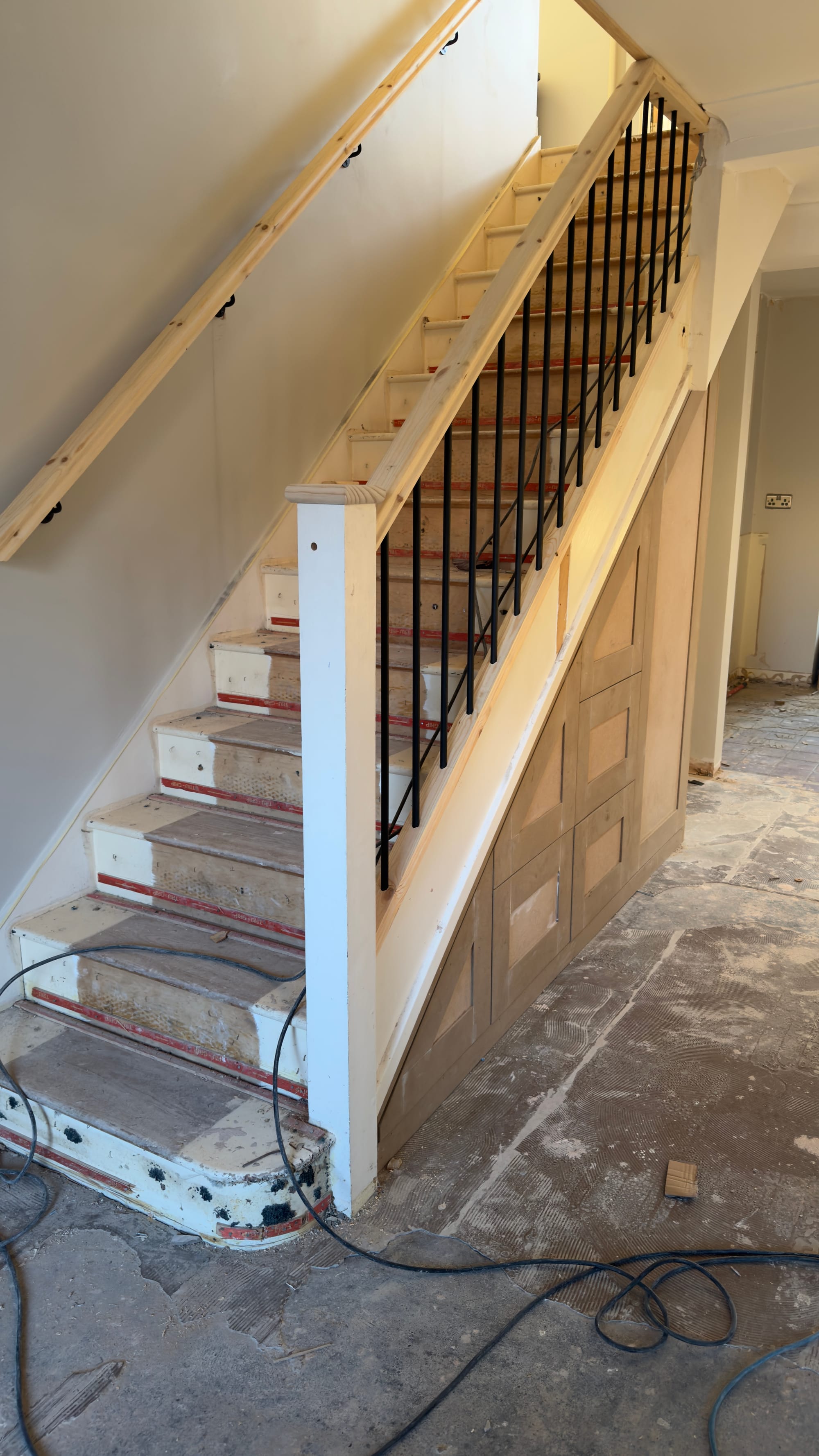 Bespoke staircase renovation in Kent with black metal spindles and under-stairs shaker storage built to maximise space.