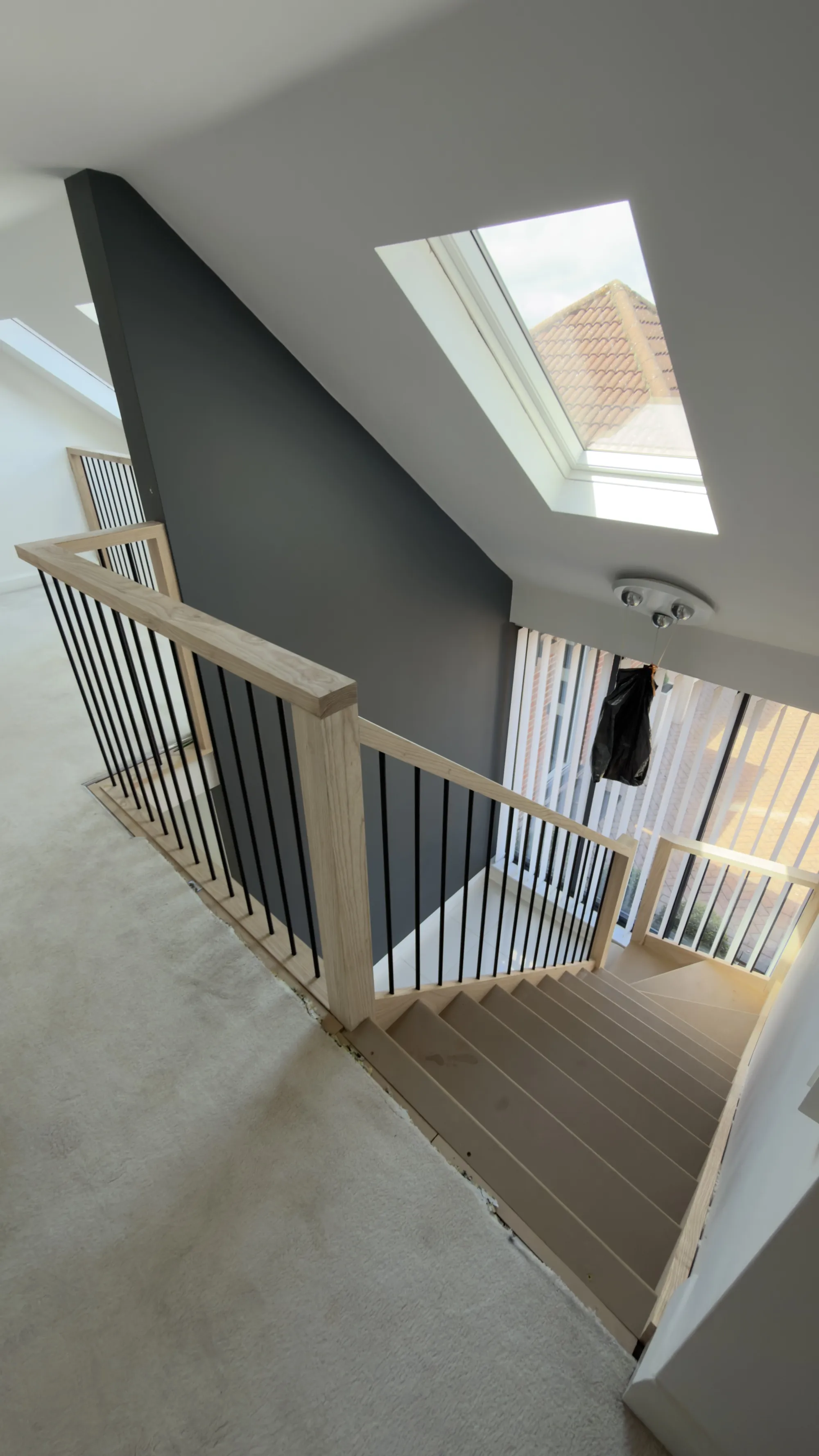 Upstairs view of ash staircase and landing balustrade with black metal spindles in Hempstead, Kent.