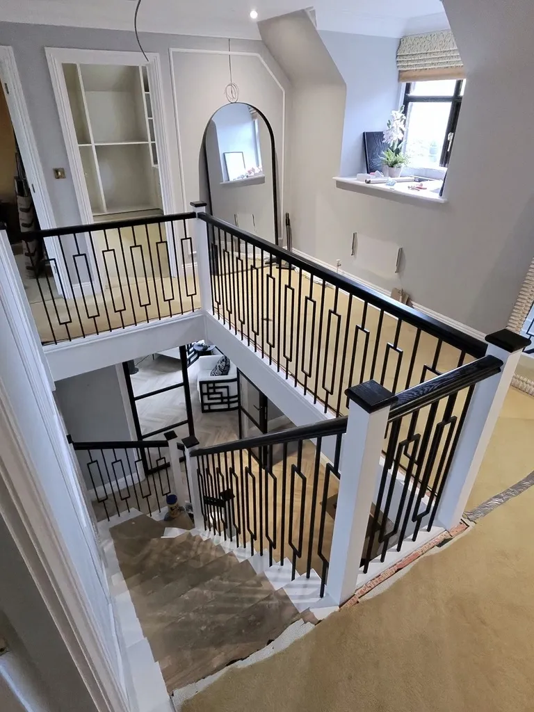 View from the landing showing ebonised oak handrails with visible grain and rectangular metal balustrading.