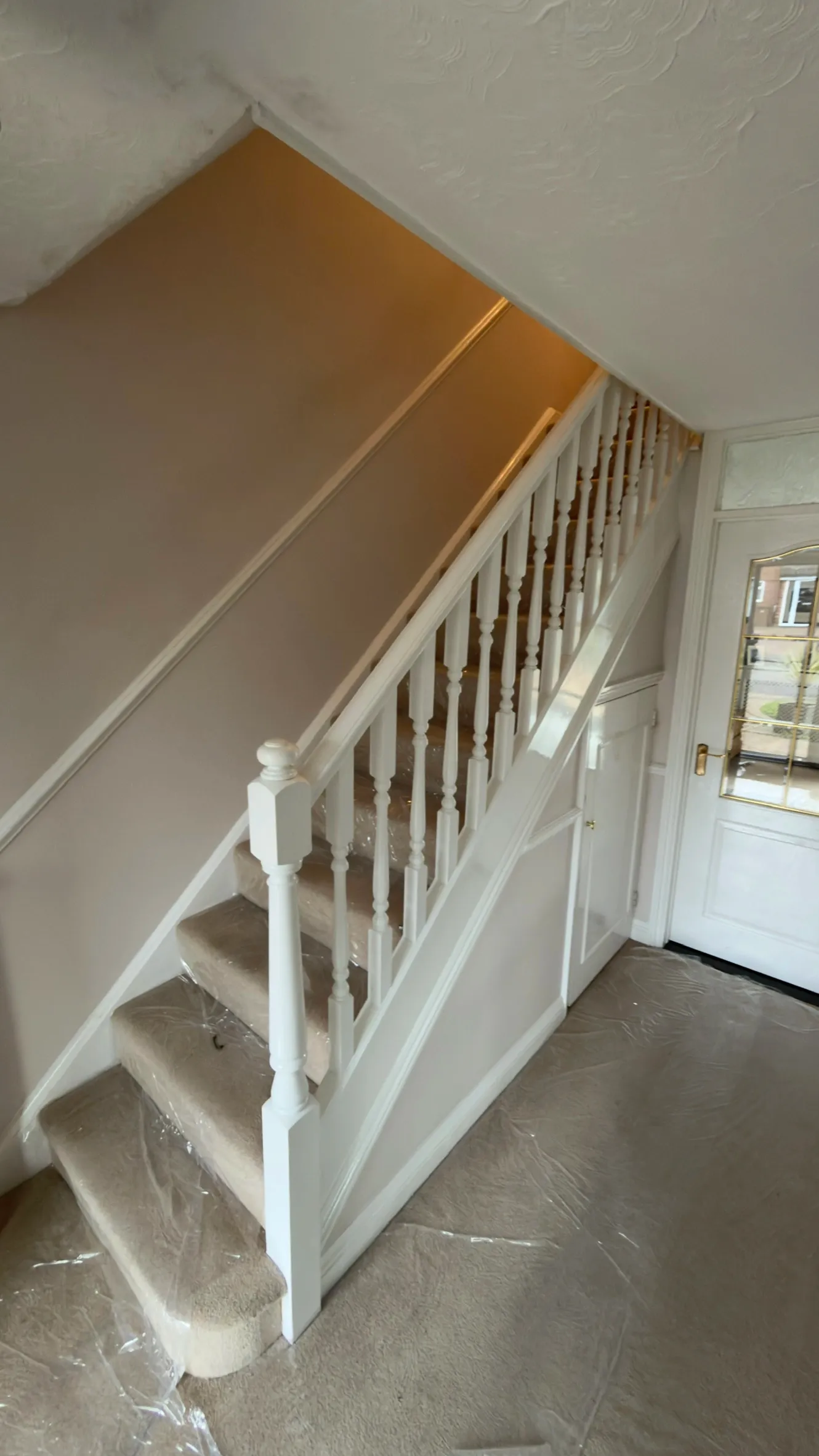 Original staircase with white turned spindles, a turned newel post and one small understairs cupboard door.