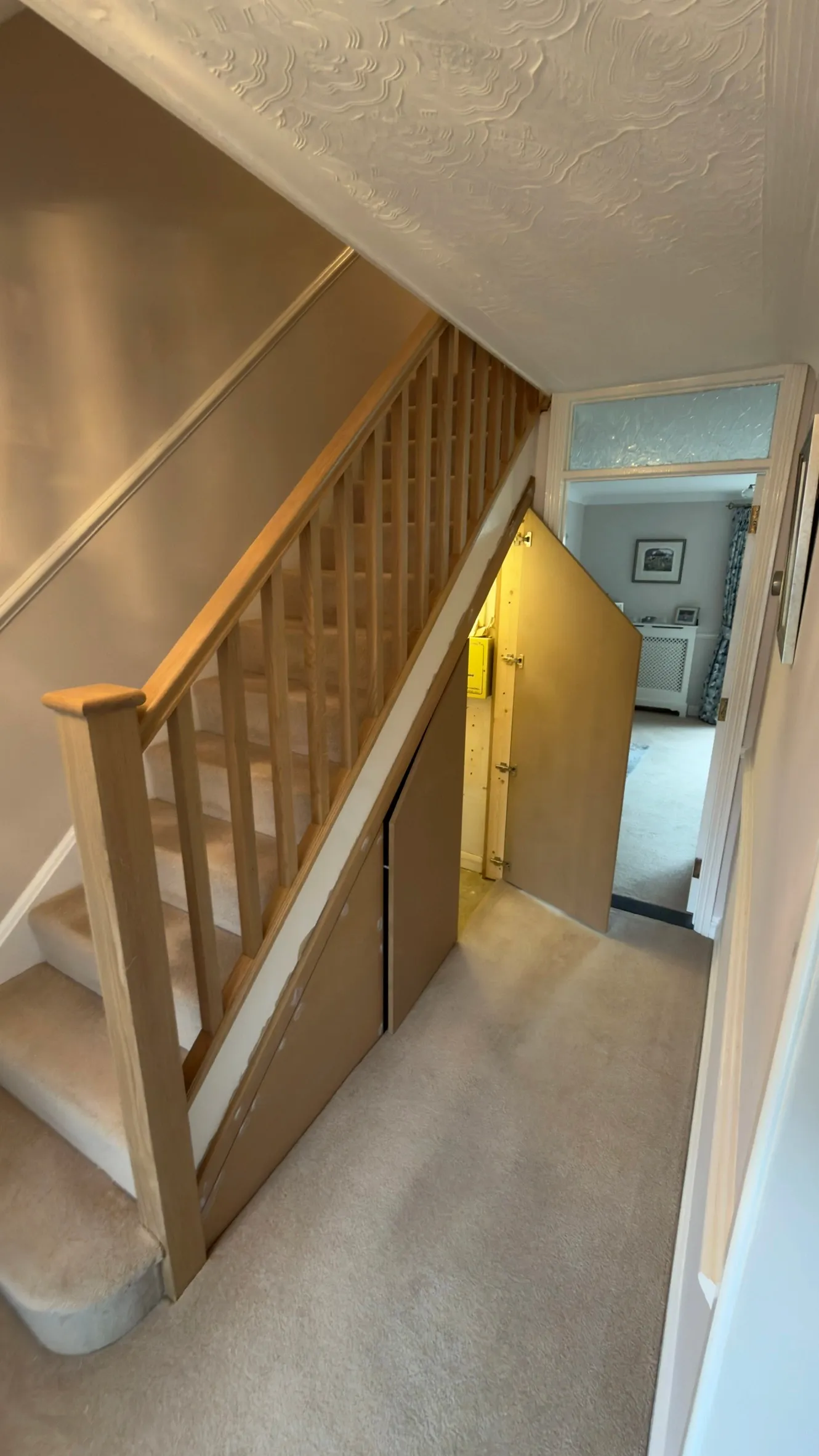New understairs cupboard doors open beneath the oak staircase, showing access to the storage space.