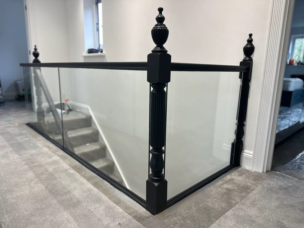 Bespoke staircase with black wooden newel posts and glass balustrades, offering a modern staircase design. Installed in Kent.